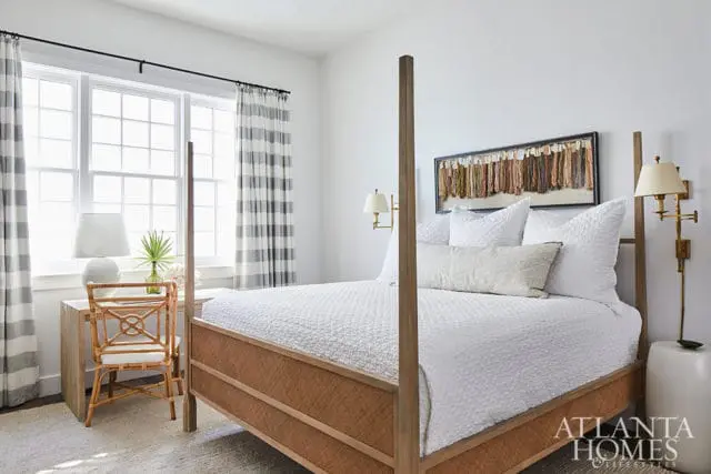 Bedroom with white bedding, a wooden four-poster bed with woven sides, and a desk with a rattan