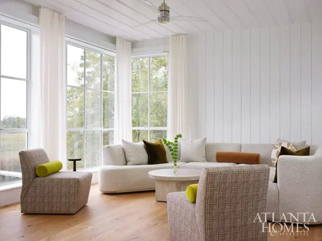 Living room with sectional sofa, armchairs, and large windows. Atlanta Homes & Lifestyles logo in
