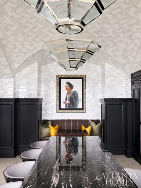 Dining room with black marble table, dark banquette, and portrait art.