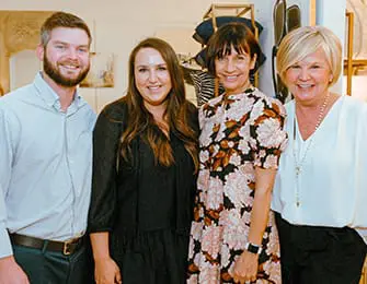 Four people posing for a photo indoors.