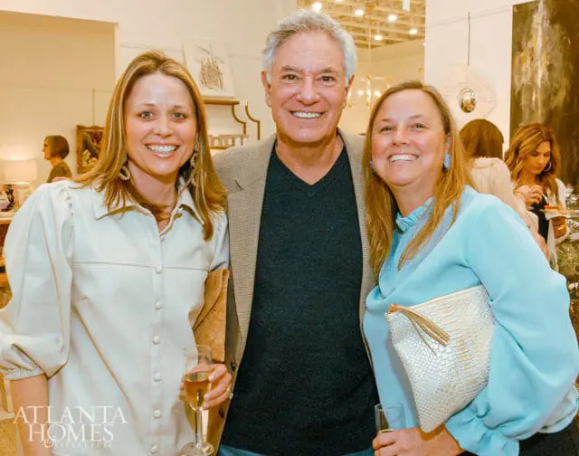 Three people smiling, two women and one man, at an event.
