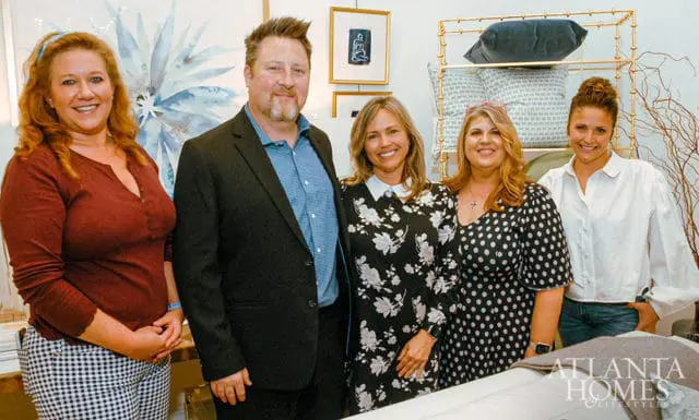 Five people posing in front of home decor items. Atlanta Homes & Lifestyles logo visible.