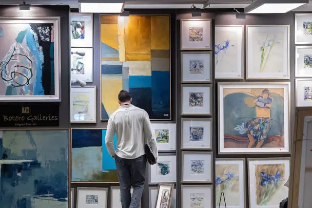Man viewing art at Botero Galleries, featuring abstract and figurative paintings.