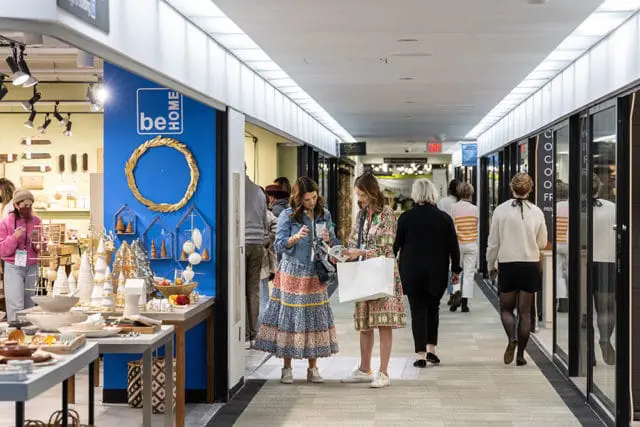 Interior market hallway with booths displaying home decor and people shopping.