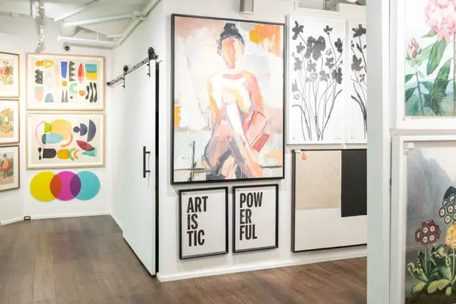 Gallery wall with abstract art, a painting of a seated figure, and framed text art