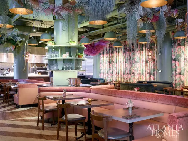 Restaurant dining room with pink banquettes, wood tables, and tropical floral curtains.