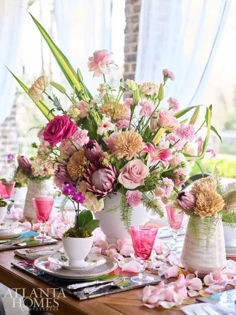 Table setting with pink flowers, pink glasses, and floral plates.