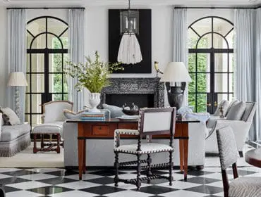 Living room with black and white checkerboard floor, light blue curtains, and ornate fireplace.
