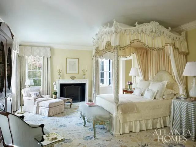 Bedroom with a four-poster bed, fireplace, and sitting area. Yellow walls and floral rug.
