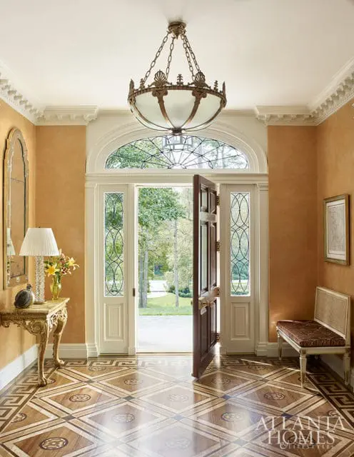 Entryway with ornate wood floor, arched transom window, and open front door.