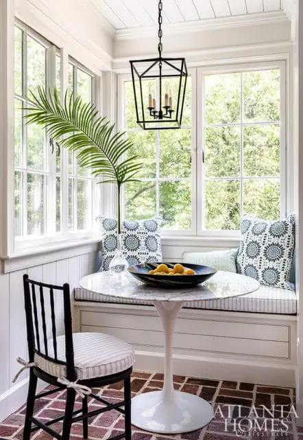 Breakfast nook with marble tulip table, black chair, banquette seating, and large windows