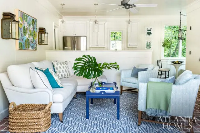 White sofa and light blue armchairs with blue and white patterned rug.