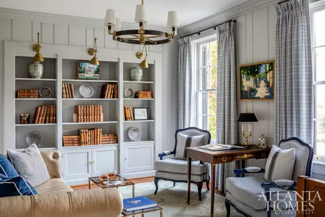 Study with built-in bookshelves, leather sofa, and plaid curtains. Atlanta Homes & Lifestyles logo