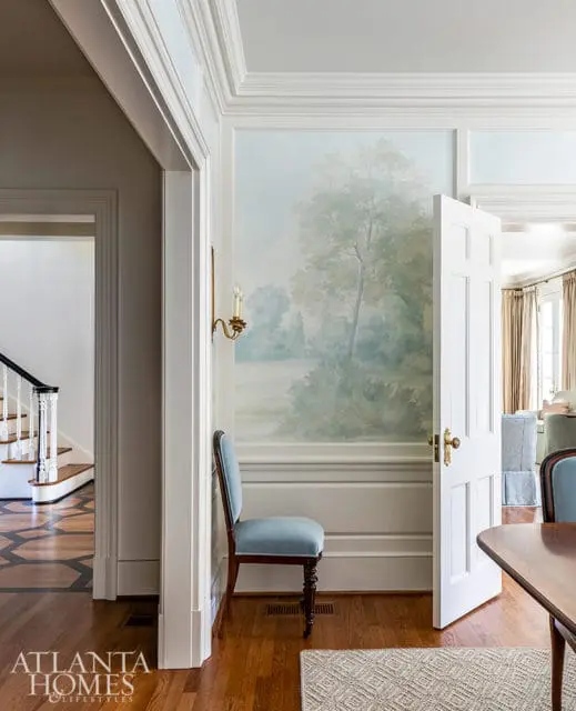 Hallway with mural, blue velvet chair, and staircase visible
