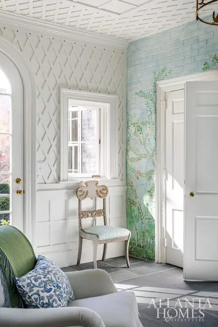 Entryway with lattice wallpaper, hand-painted brick mural, and antique chair