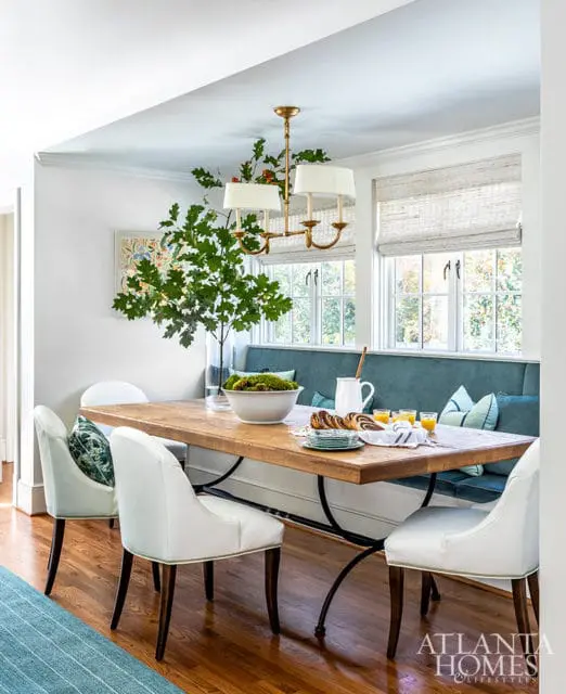 Dining room with wood table, white chairs, and teal banquette seating.