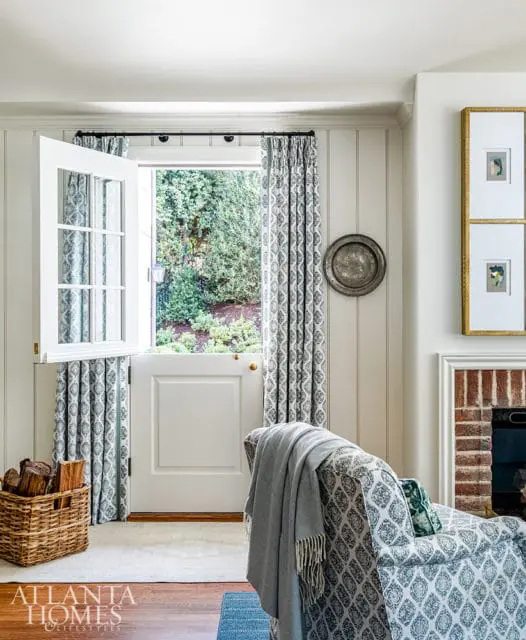 Living room with open Dutch door, patterned armchair, and fireplace.