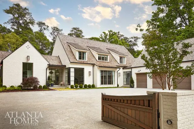 White brick house with wood shake roof, large windows, and attached garage.