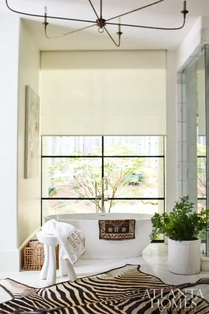 White freestanding bathtub with a patterned towel and a zebra rug in a modern bathroom.