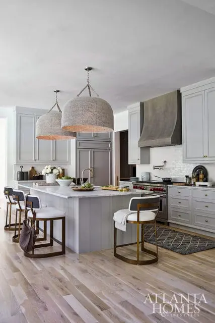 Gray kitchen with marble island, woven pendant lights, and stainless steel appliances.