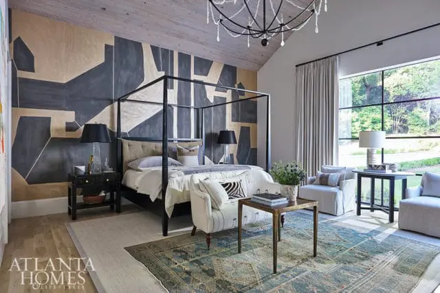 Bedroom with abstract mural, four-poster bed, and large window overlooking trees.