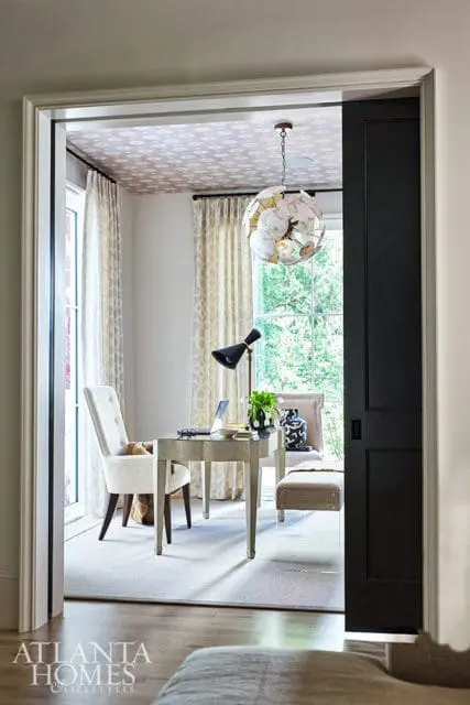 Home office with patterned ceiling, desk, chair, and chandelier.