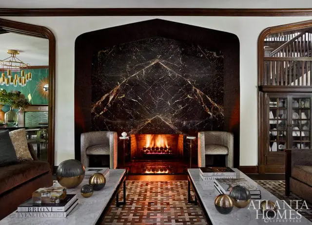 Living room with dark marble fireplace, two chairs, and marble coffee tables.