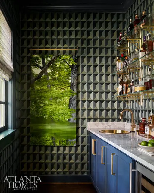 Bar area with blue cabinets, marble countertop, gold hardware, and geometric wallpaper.