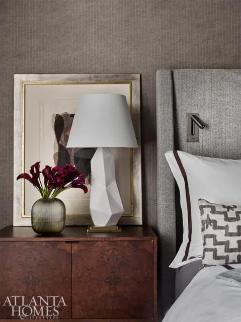 Bedroom with gray upholstered headboard, abstract art, and geometric pillow.