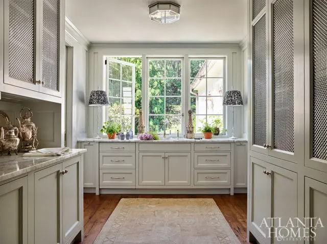 Light gray kitchen with marble countertops, paneled cabinets, and a large window overlooking