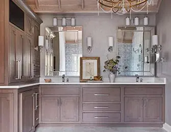 Gray double vanity with two sinks, mirrored backsplash, and ornate chandelier above