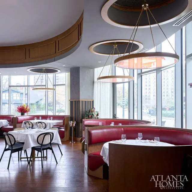 Restaurant dining room with red leather booths, white tablecloths, and modern circular pendant