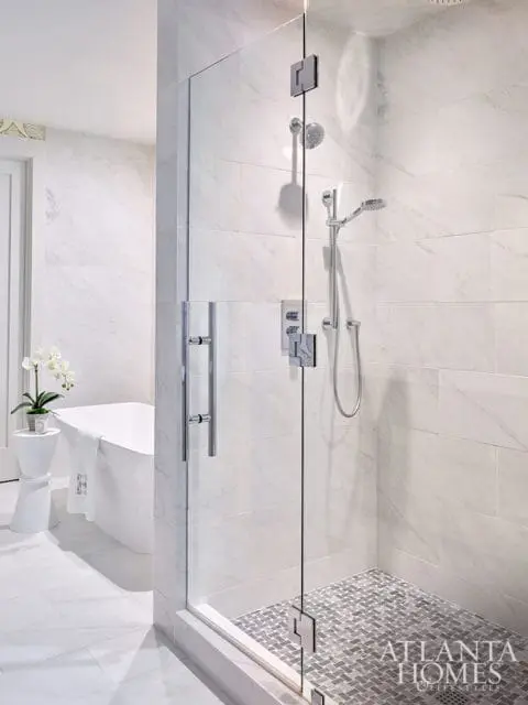 White marble bathroom with glass shower, freestanding tub, and mosaic tile floor