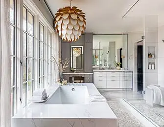 Modern bathroom with white soaking tub, marble vanity, glass shower, and gold chandelier