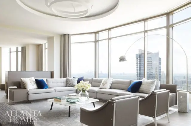 Gray sectional sofa with blue and patterned pillows, marble coffee table, and floor lamp