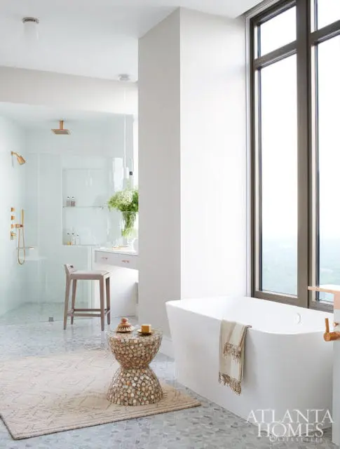 Modern white bathroom with freestanding tub, glass shower, and mosaic accent table.