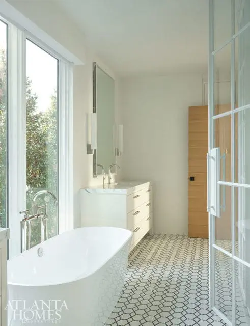 White freestanding tub, vanity with marble countertop, and geometric tile floor in a modern