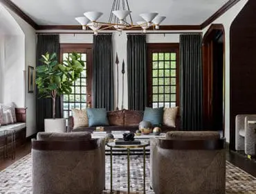 Living room with dark wood trim, built-in window seat, brown velvet sofa, patterned armchairs, and