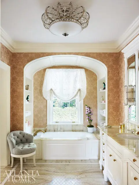 Bathroom with a white soaking tub, ornate chandelier, and marble vanity.