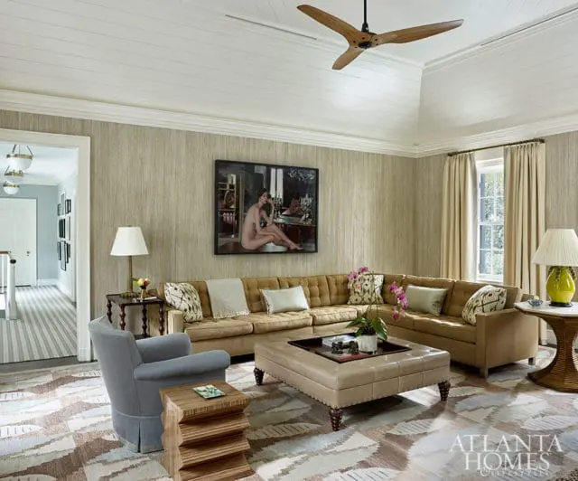Tan sectional sofa with tufted cushions, large ottoman coffee table, and abstract rug.