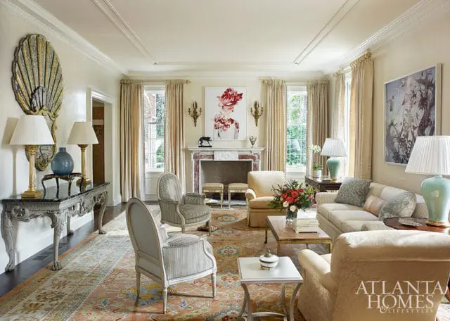 Living room with fireplace, ornate console table, sofa, armchairs, and oriental rug.