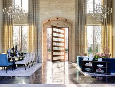 Entryway with stone walls, open wood door, dining table, and blue sofa.