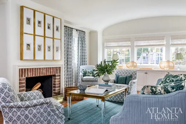 Living room with brick fireplace, patterned armchairs, blue sofa, and Atlanta Homes & Lifestyles