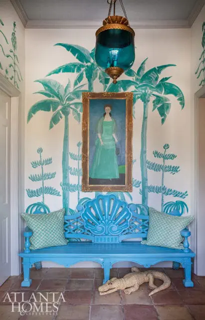 Hallway with turquoise palm tree mural, blue bench, and framed portrait.