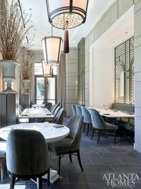 Dining room with plush gray chairs, white tables, and ornate pendant lights.