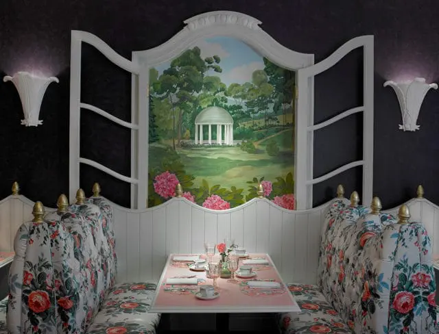 Dining booth with floral upholstery and a mural of a gazebo and rhododendrons