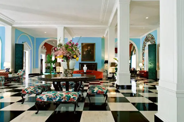 Lobby with black and white checkered floor, blue walls, floral chairs, and large floral arrangement