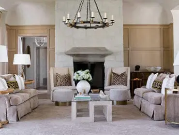 Living room with stone fireplace, two sofas, two armchairs, and a glass coffee table.