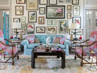 Turquoise tufted sofa with patterned pillows, flanked by chairs with pink zebra print upholstery.