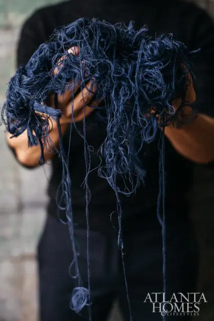 Hands holding a tangled bundle of dark blue thread
